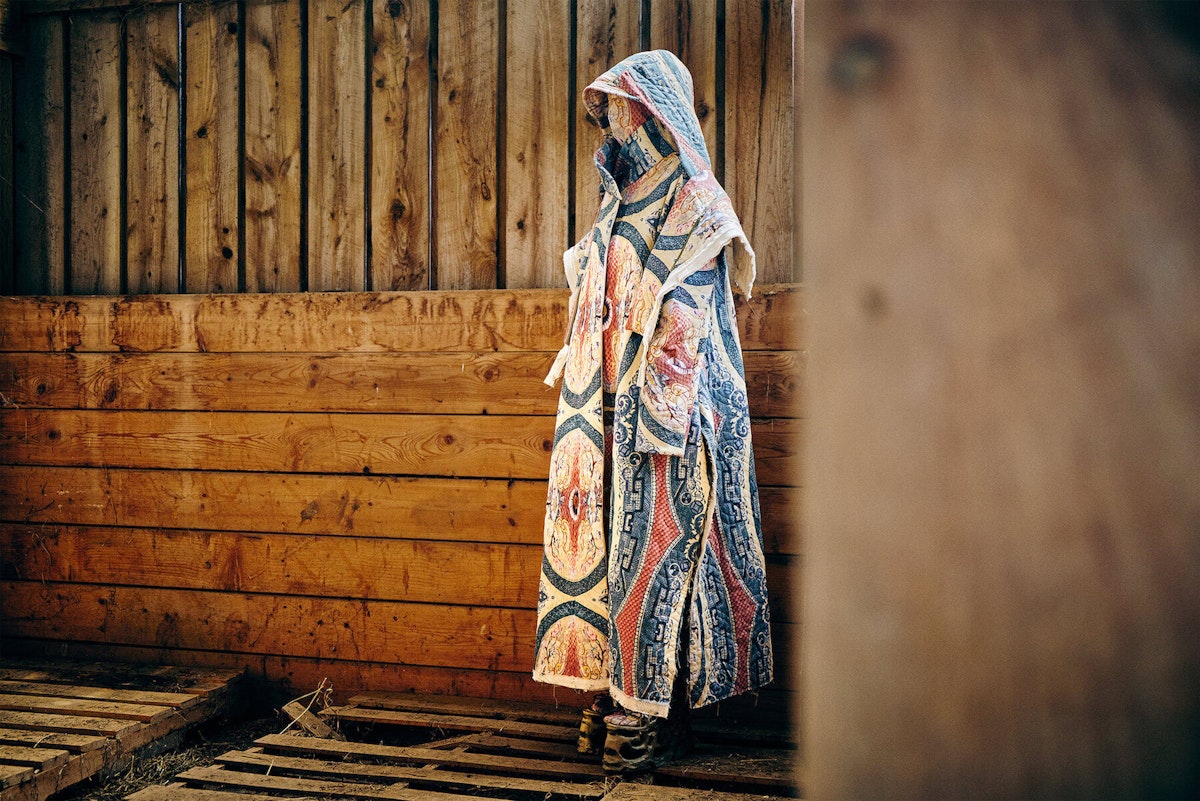 A quilted, red and blue-patterned garment against a wood backdrop